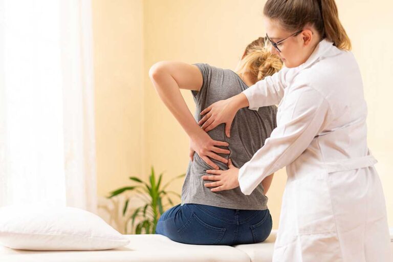 A person stretching their back in a bright living room with a supportive chair and natural light.